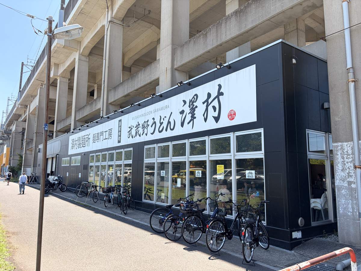 高架下にある武蔵野うどん澤村の黒い横長の店舗外観