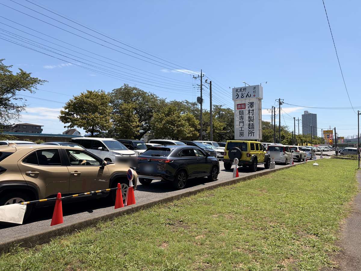 休日昼前で満車になった澤村の駐車場と、番号のついたコーンが並ぶ車の待機列