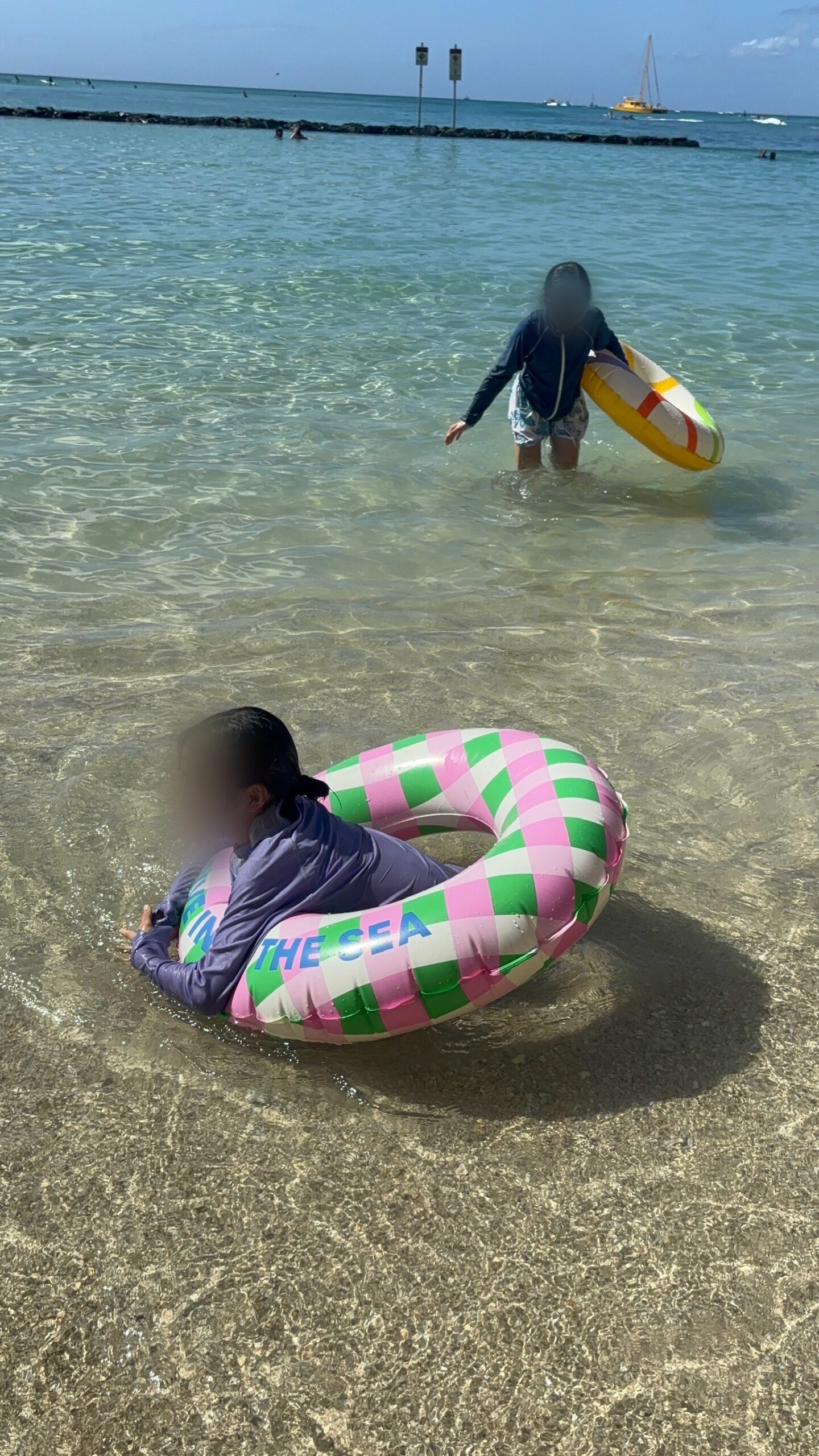 ワイキキビーチの浅瀬に浮かぶ浮き輪と子ども
